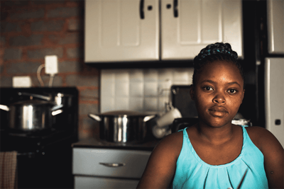 Ayanda stands in her kitchen safe after almost being deceived by a potential trafficking situation.